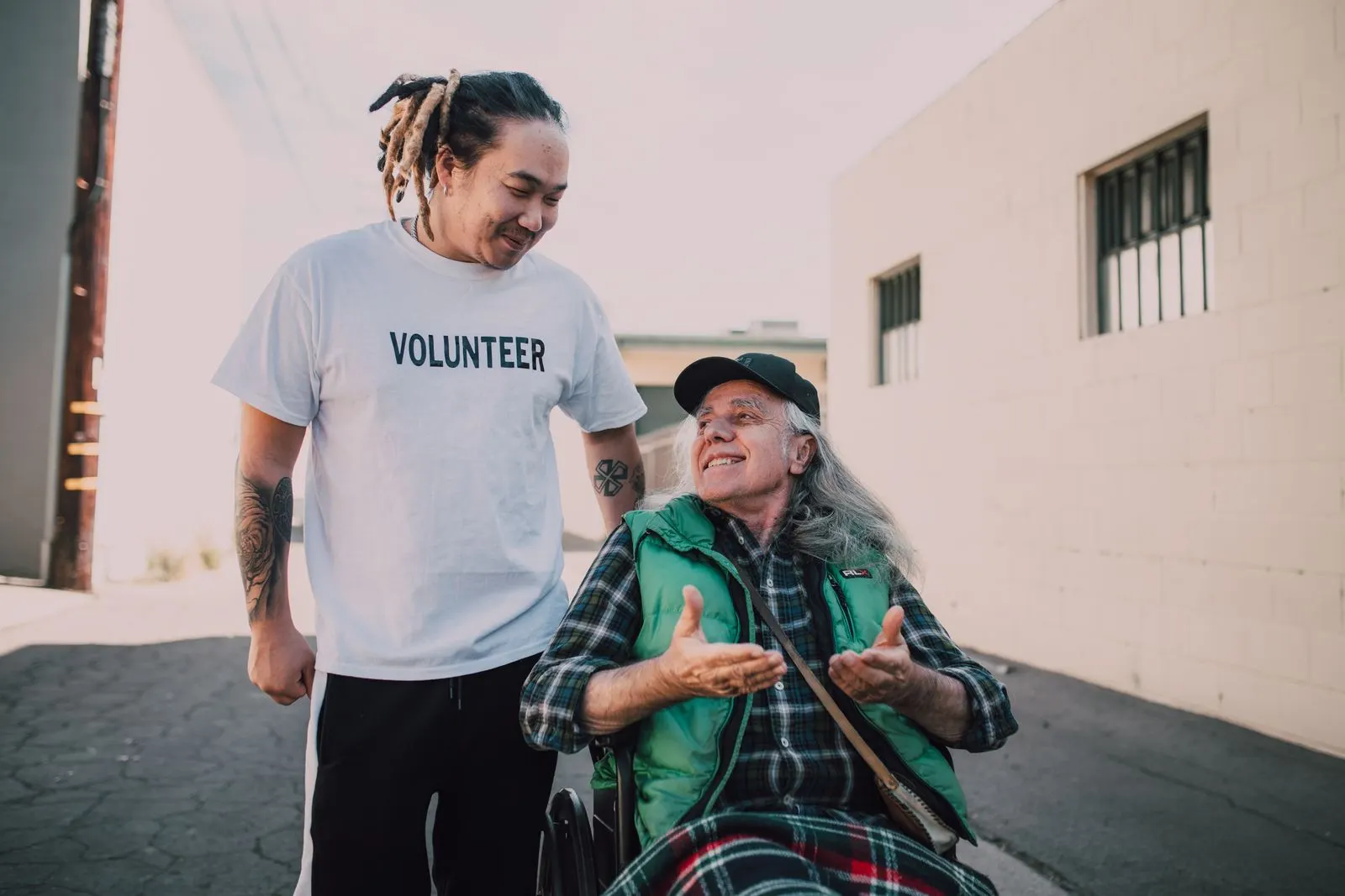 A young volunteer sharing a laugh with an older man in a wheelchair